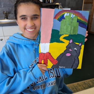 Riley shows off her finished painting for the DaVinci Art Show "Along the Yellow Brick Road". Opening reception March 9, 2024