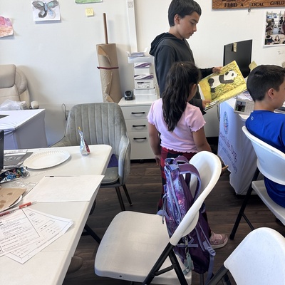 Youth volunteer reading at homework club to a little one